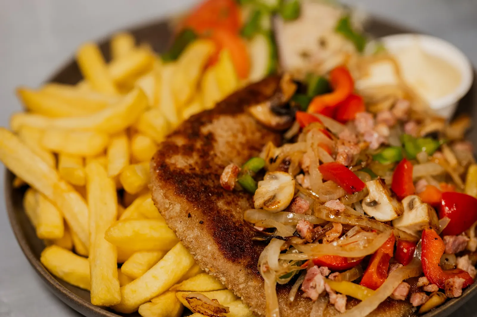 Plate boerenschnitzel met friet, champignon, spek, paprika en ui